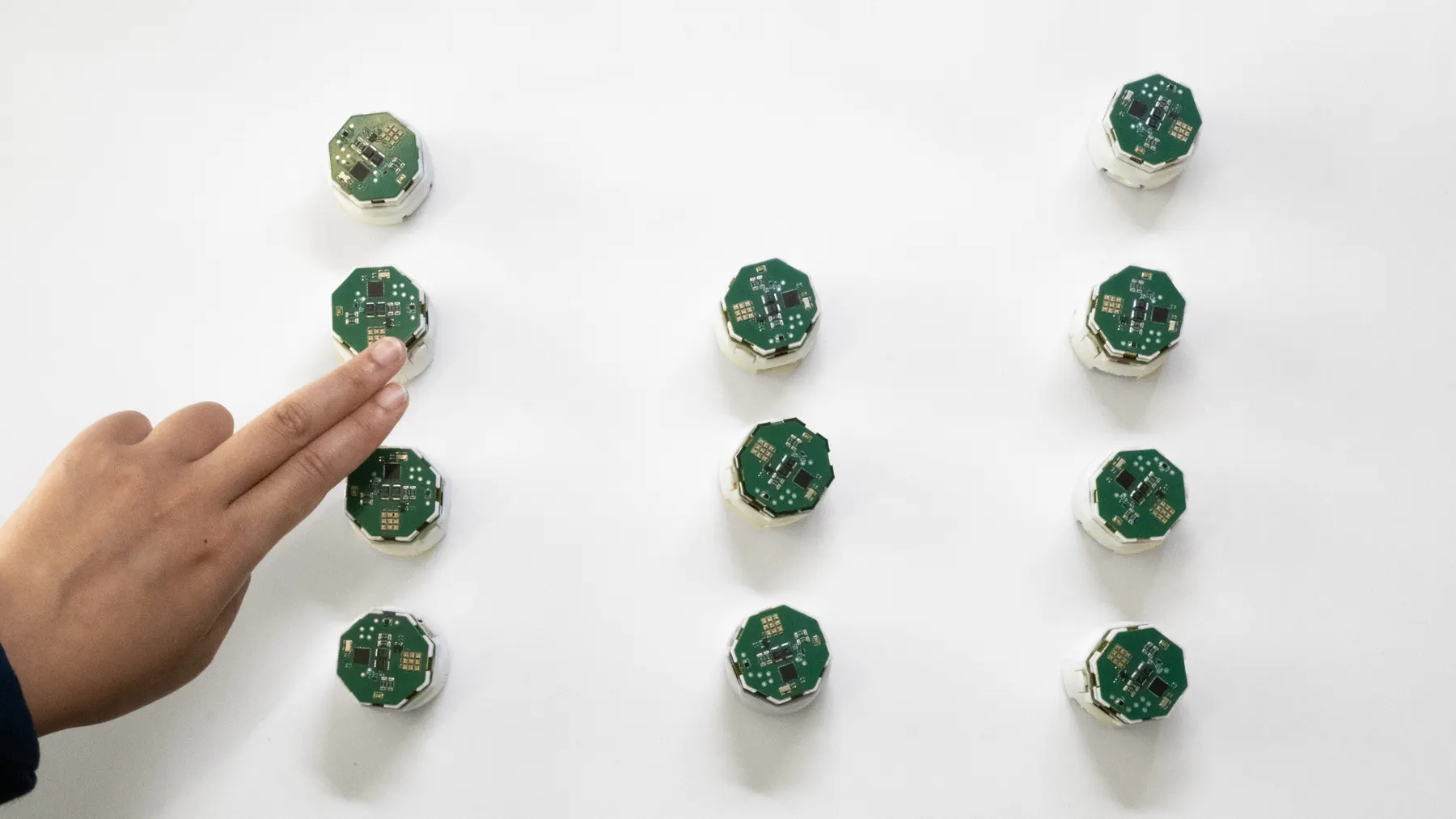 A hand pointing at robots arranged in columns of different heights, like a bar chart.