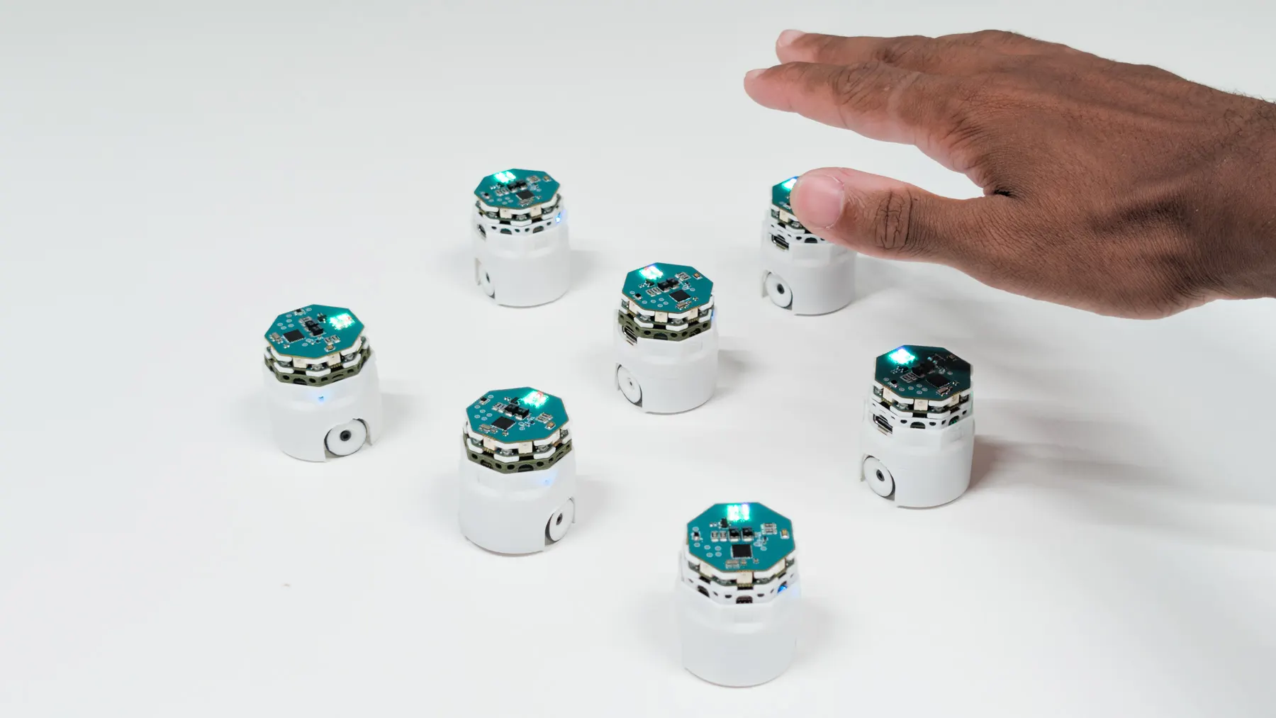 A hand passing above a small group of robots.